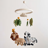 A felt baby mobile, 'Felt Baby Mobile - Safari Jungle', is suspended from a white string attached to a circular wooden frame at the top. The mobile features a giraffe, zebra, and elephant in a Safari Jungle theme, crafted with soft wool felt materials.