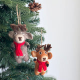 Two cute Christmas reindeer felt ornaments are suspended by a rustic jute string on a festive Christmas tree, adorned with green needles and pine cones. These charming light brown reindeers feature brown antlers, a bright red scarf, perky ears, a dark brown nose, and black hooves, adding playful holiday cheer.