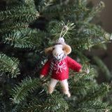 A charming needle felted mouse ornament is nestled among the lush green needles of a Christmas tree. This handcrafted felt mouse, wearing a gray scarf, a red sweater with a white snowflake, and a hat, features light brown ears and legs, and is ready to hang with its white cotton string.