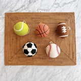 A set of five wool felt American popular sports ball ornaments rests on a woven mat against a marble background. These 3-inch, 3D needle felted ornaments include a yellow tennis ball, orange basketball, brown football with white accents, classic black and white soccer ball, and white baseball with red stitching. Each handcrafted sports ornament has a jute thread for easy hanging.
