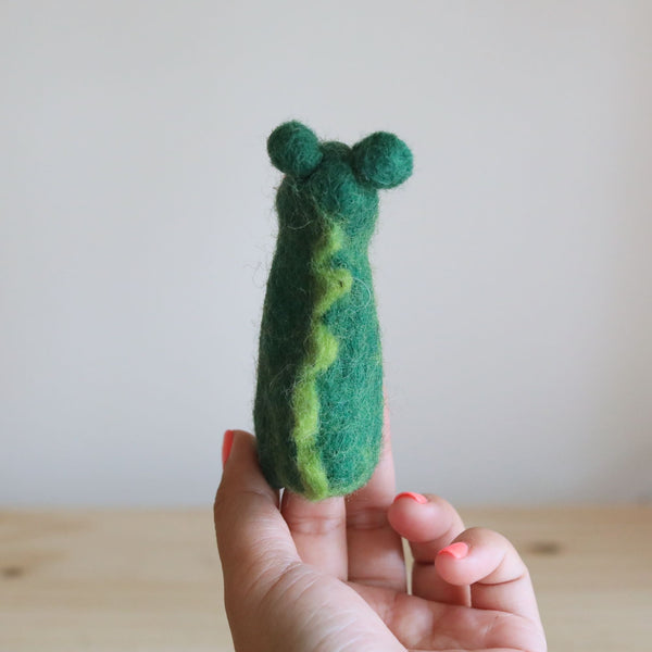 A small, green felt gator finger puppet resting on a plain background, crafted from wool felt with a soft texture. The friendly expression features a wide smile and big eyes, perfect for imaginative play and storytelling.