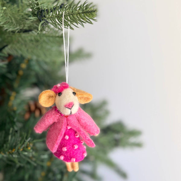 A handcrafted needle felted mouse Christmas ornament hangs on a vibrant green Christmas tree, set against a soft, bright background. This charming wool felt ornament, made from organic wool, is 3D with a distinctive needle-felted and hand-stitched texture. It is suspended by a delicate white cotton string, evoking a cozy and festive mood.