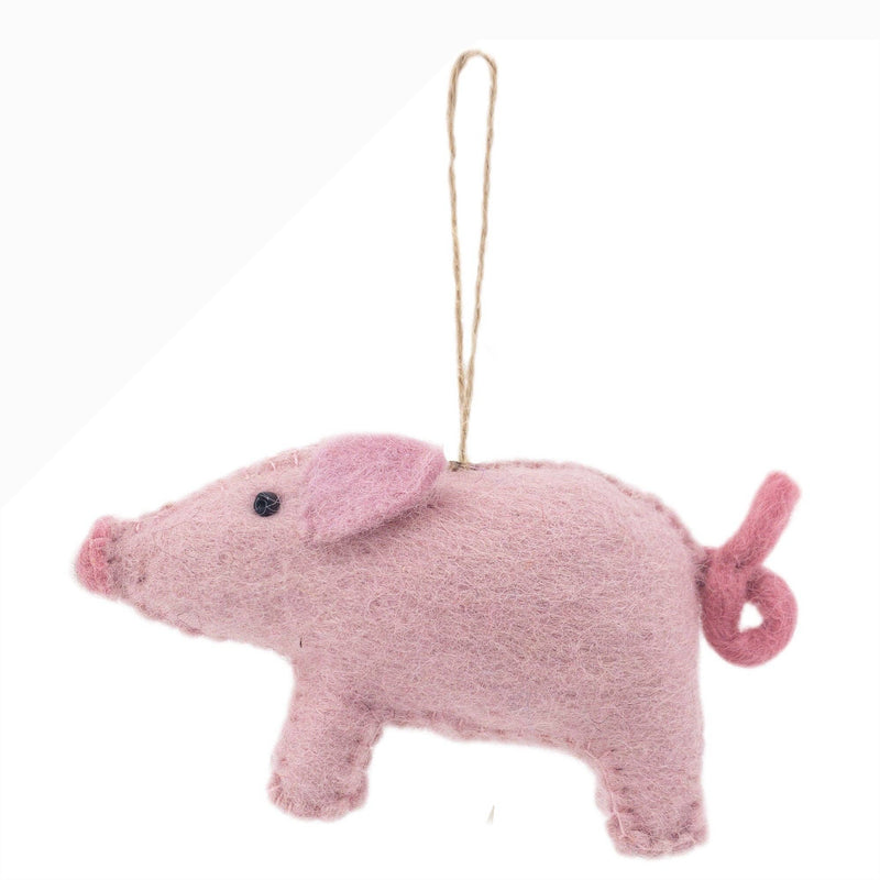 A charming handmade pig felt Christmas ornament is suspended by a jute string against a bright white backdrop. This wool felt pig ornament is a soft pink, accented with darker pink on its ears and snout. It features a curly tail, legs, and a black bead eye, creating a soft and inviting look.
