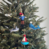 A cheerful felt pirate ornament hangs on a festive Christmas tree, bringing a playful touch. This handcrafted felt ornament features a red bandana with white dots and is attached with a jute string, adding a rustic charm among the warm white lights.