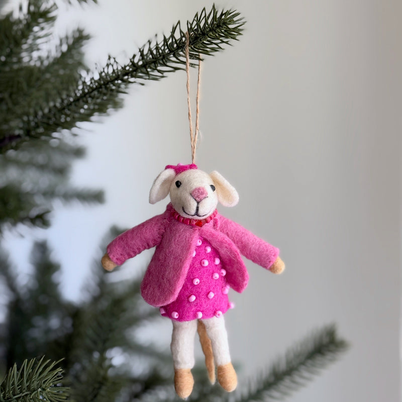A handcrafted needle felted mouse Christmas ornament hangs on a vibrant green Christmas tree, set against a soft, bright background. This charming wool felt ornament, made from organic wool, is 3D with a distinctive needle-felted and hand-stitched texture. It is suspended by a delicate white cotton string, evoking a cozy and festive mood.