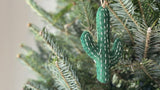 A handmade felt cactus ornaments by Ganapati Crafts hanging on a  Christmas tree