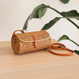 A Turbo Bag  in Bali Rattan Crossbody Bag collection by Ganapati Crafts Co. handwoven in Bali is sitting on a wood table