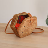 Bali Hexagon Rattan Crossbody Bag by Ganapati Crafts Co. handwoven by skilled artisans in Bali is sitting on a wood table