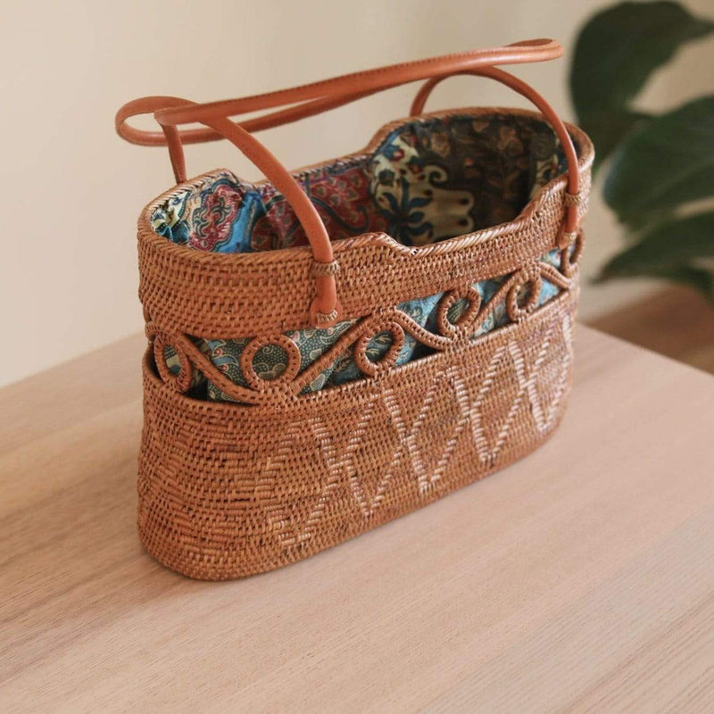 Bali Rattan Circle Decor Handbag handmade by Ganapati Crafts Co. in Bali where all the Bali Rattan bags are made is sitting on a wood table looking stylish