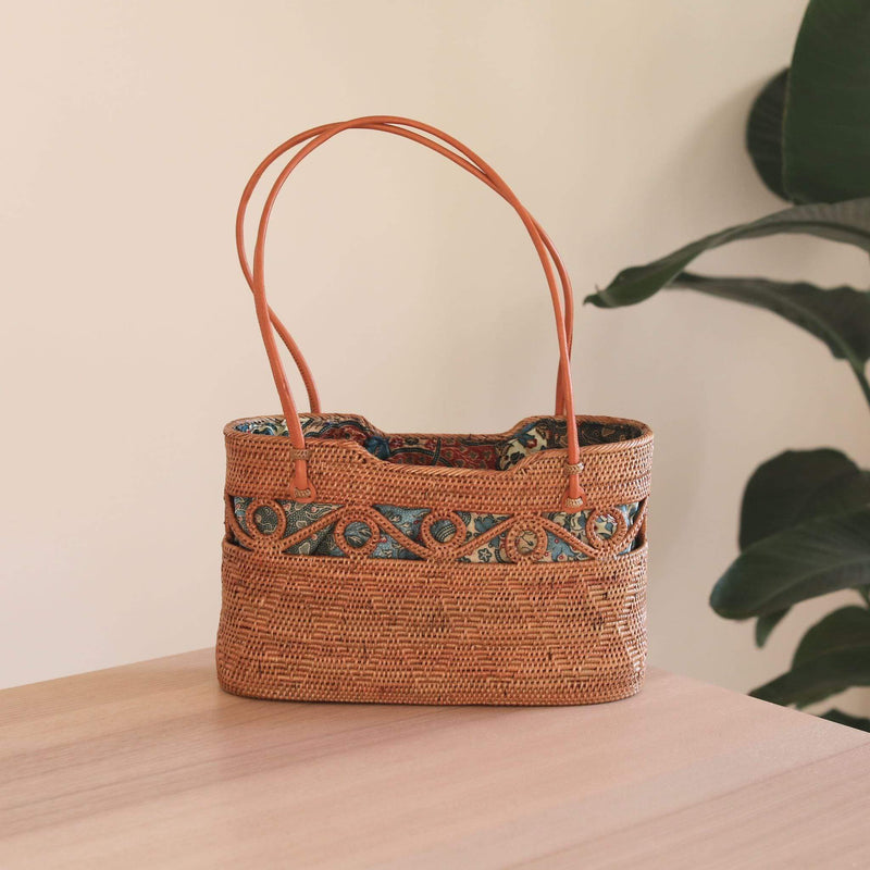 Bali Rattan Circle Decor Handbag handmade by Ganapati Crafts Co. in Bali where all the Bali Rattan bags are made is sitting on a wood table looking stylish