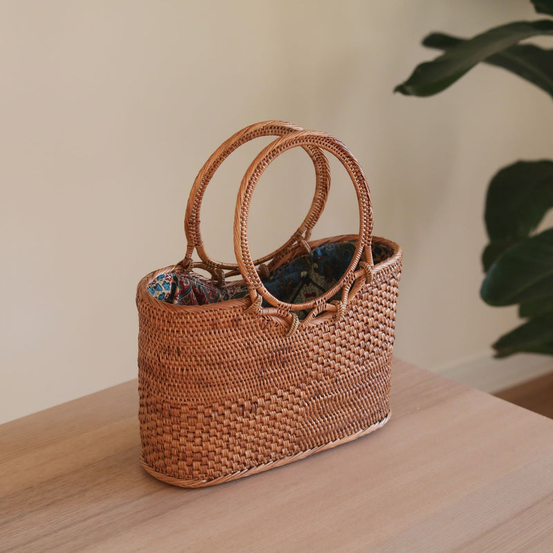 The Kelsey Bali Rattan Handbag handmade by Ganapati Grafts in Bali where all the Bali Rattan Bags are made is sitting n a table looking stylish