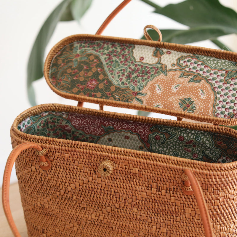 Bali Rattan Tote Bag With Lid handmade by Ganapati Crafts Co. in Bali is sitting on a wood table looking stylish