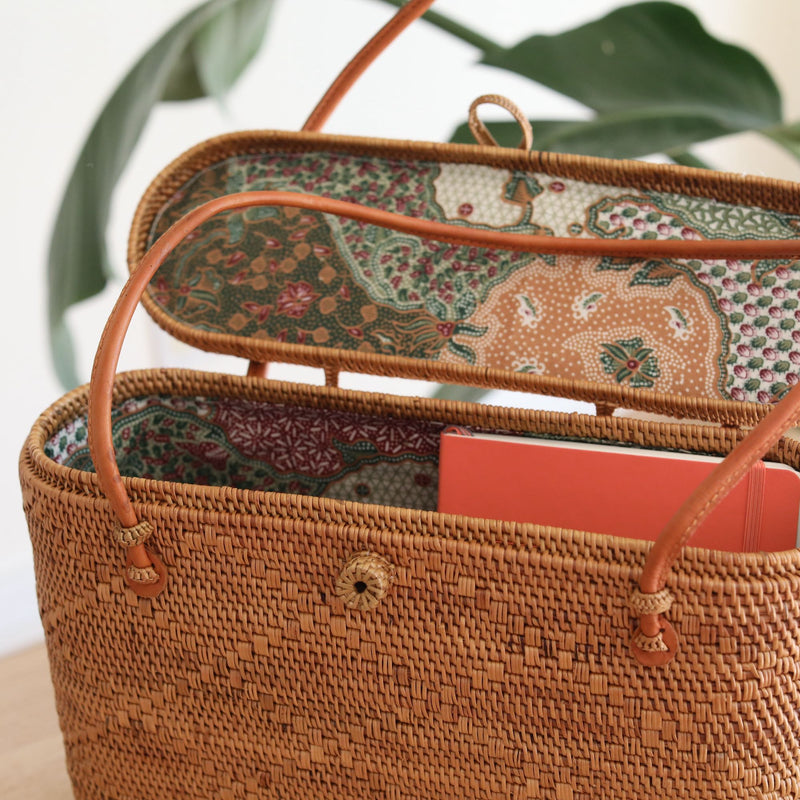 Bali Rattan Tote Bag With Lid handmade by Ganapati Crafts Co. in Bali is sitting on a wood table looking stylish