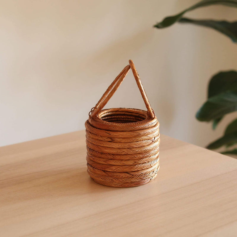 Bali Round Rattan Clutch handmade by Ganapati Crafts Co. in Bali is sitting on a wood table looking stylish and instagramable