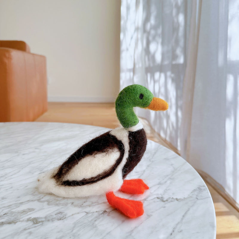 Needle Felted Duck Christmas Ornament handmade by Ganapati Crafts Co. in Nepal sitting on a white table waiting to be put on a Christmas tree